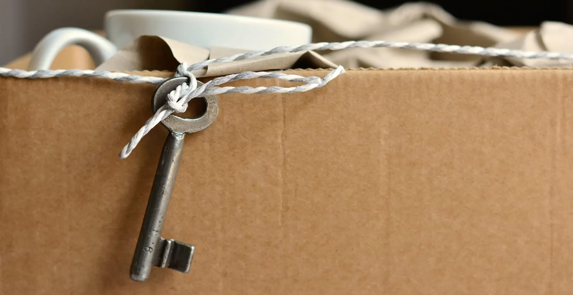 Wohnungsschlüssel auf einem verschnürten Umzugskarton zur Übergabe nach der Wohnungsauflösung